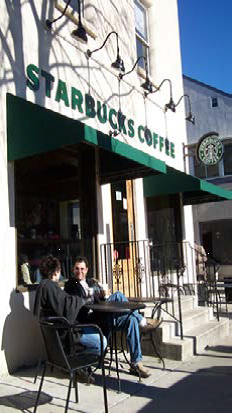 two people sitting at a table outside a starbucks coffee shop